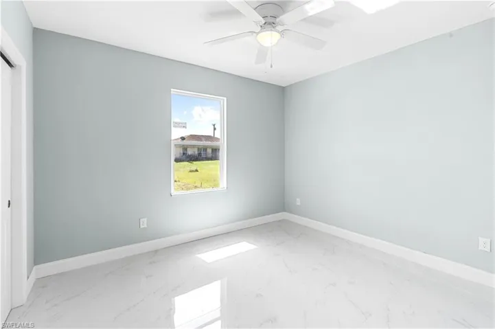 Spare room with baseboards, marble finish floor, and ceiling fan
