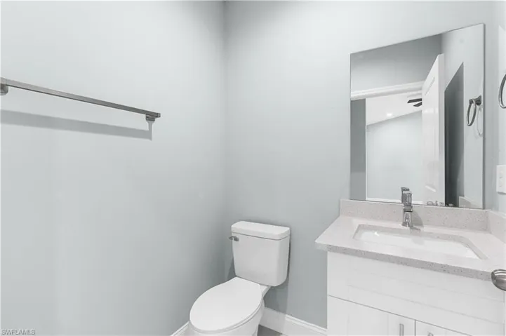 Bathroom with toilet, vanity, and baseboards