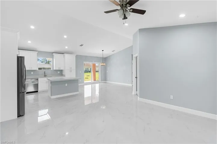 Kitchen with marble finish floor, stainless steel dishwasher, open floor plan, freestanding refrigerator, and light countertops