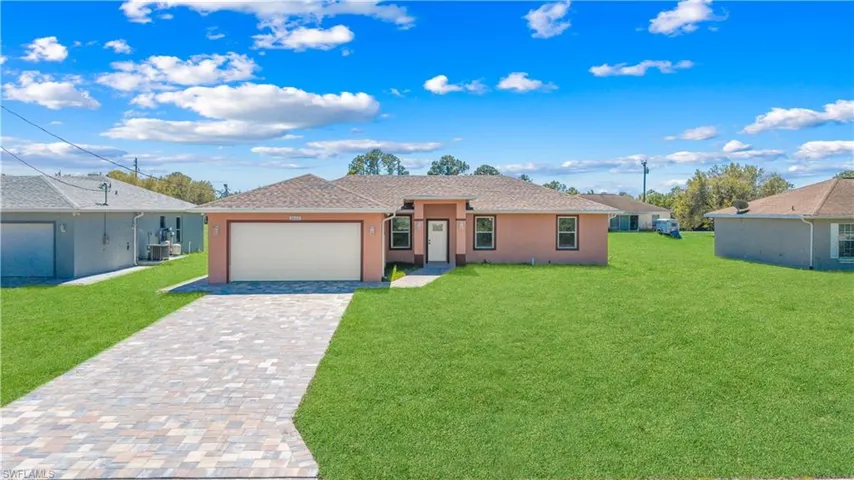 Ranch-style house featuring a front yard, decorative driveway, a garage, and stucco siding