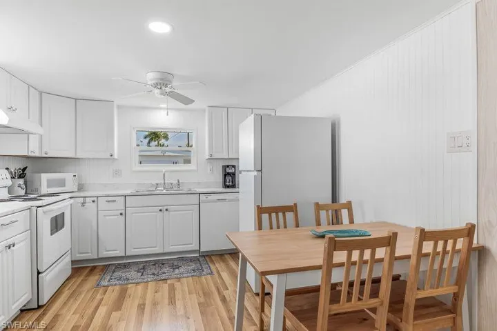 Kitchen featuring updated white cabinetry, white appliances, wood-finish laminate flooring, recessed lighting, and a ceiling fan.