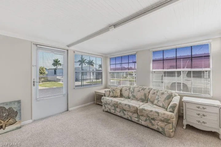 Extra room that could be a potential office/den/ bedroom featuring multiple windows with horizontal blinds, a neutral carpeted floor, and a white beadboard ceiling with exterior door to the outside.