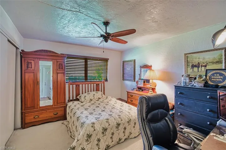 Bedroom with light carpet, a textured ceiling, ceiling fan, and a desk
