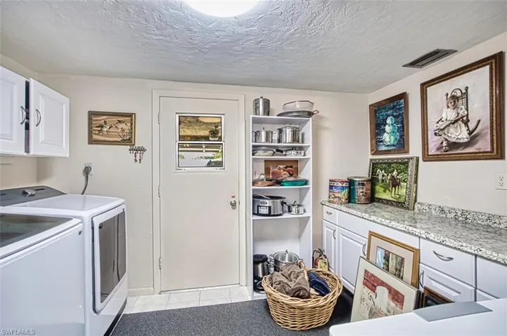 Laundry room with cabinet space, washer and dryer, light tile patterned floors, and a textured ceiling
