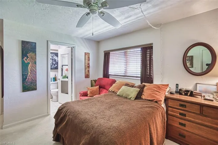 Bedroom with light colored carpet, connected bathroom, and ceiling fan