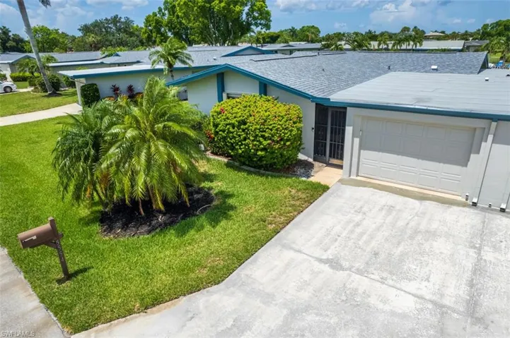 Ranch-style house with an attached garage, driveway, a front yard, a shingled roof, and stucco siding