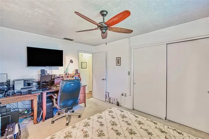 Office space featuring a ceiling fan, light carpet, and a textured ceiling