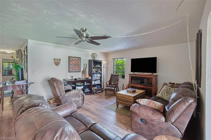 Living room featuring wood finished floors, a ceiling fan, and a textured ceiling