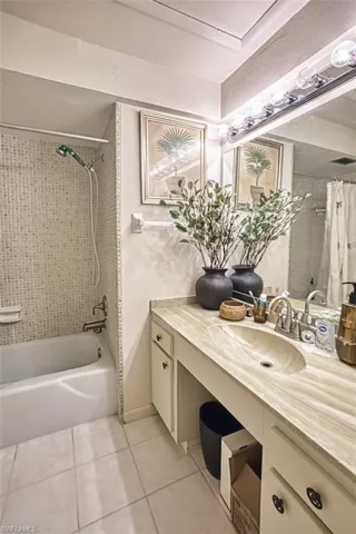 Bathroom with tile patterned flooring, shower / bath combination with curtain, and vanity