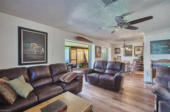 Living area with wood finished floors, a textured ceiling, a chandelier, and ceiling fan