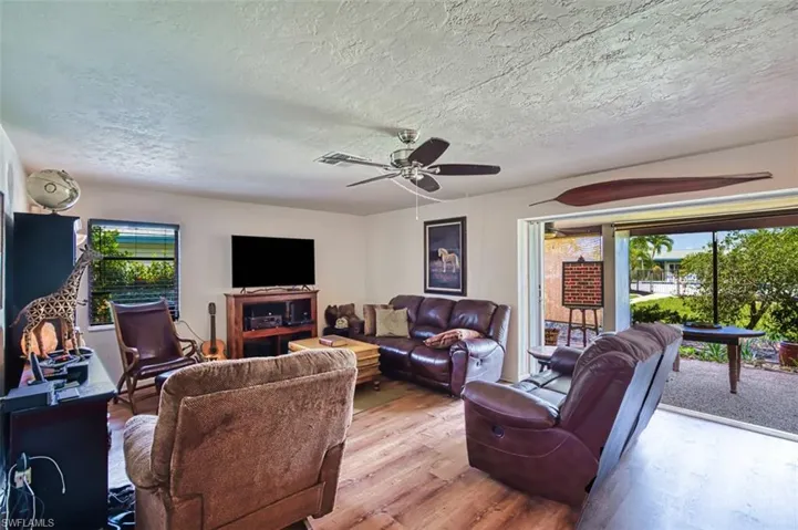 Living area featuring wood finished floors, a textured ceiling, and a ceiling fan