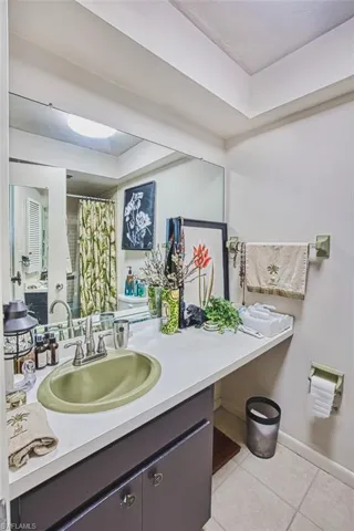 Bathroom with tile patterned floors, vanity, a raised ceiling, and curtained shower