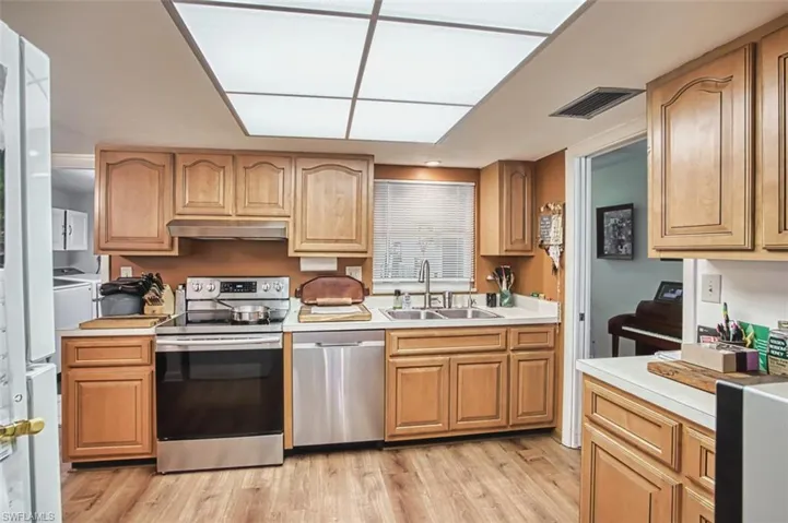 Kitchen featuring appliances with stainless steel finishes, light countertops, light wood-style flooring, and under cabinet range hood