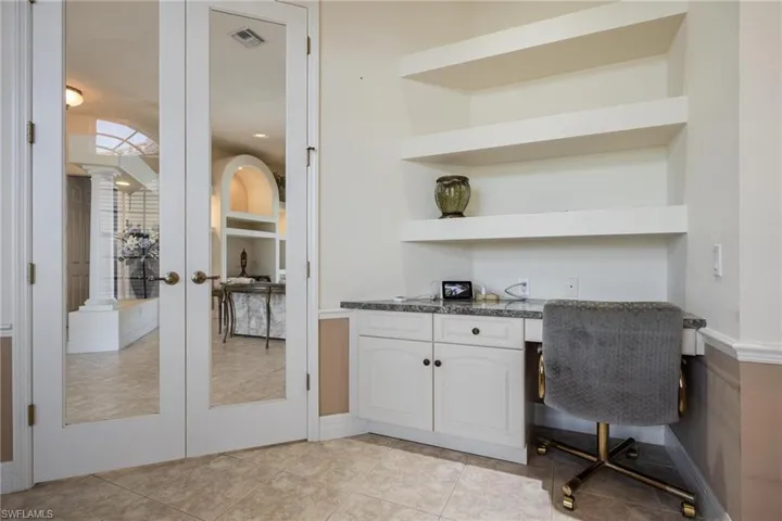 Office/Den with Built-In Desk and Bookshelves and French doors giving you a view of the living room