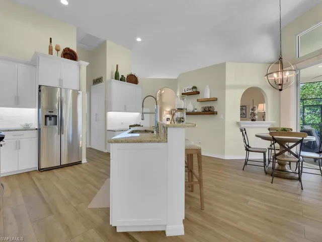 Kitchen featuring light hardwood / wood-style floors, white cabinetry, stainless steel fridge with ice dispenser, and decorative light fixtures