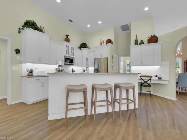 Kitchen featuring a center island with sink, light hardwood / wood-style floors, stainless steel appliances, and white cabinets
