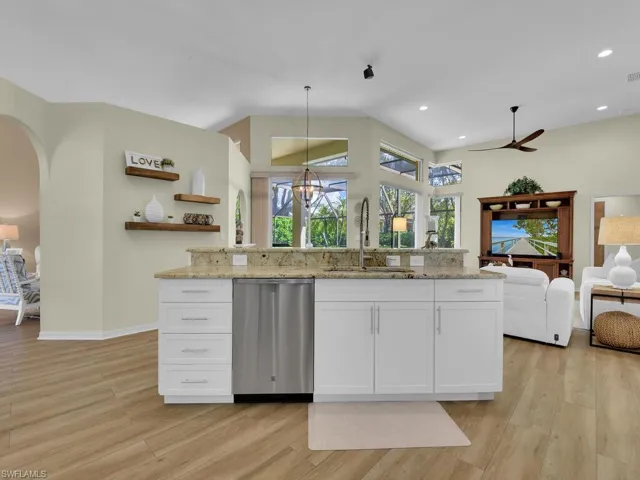 Kitchen with white cabinets, pendant lighting, sink, stainless steel dishwasher, and light wood-type flooring