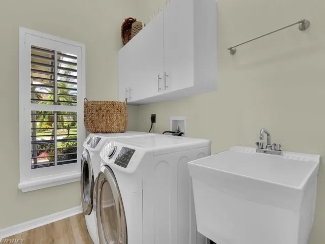 Laundry area featuring washer and clothes dryer, plenty of natural light, sink, and cabinets