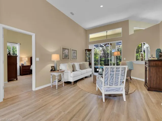 Living room with high vaulted ceiling and light hardwood / wood-style floors