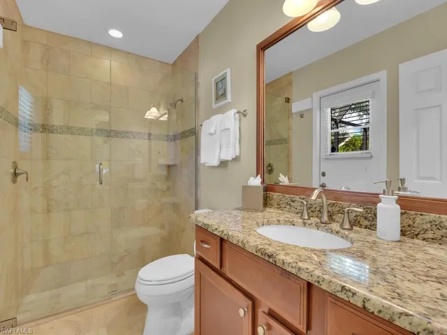 Bathroom featuring vanity, toilet, and a shower with door