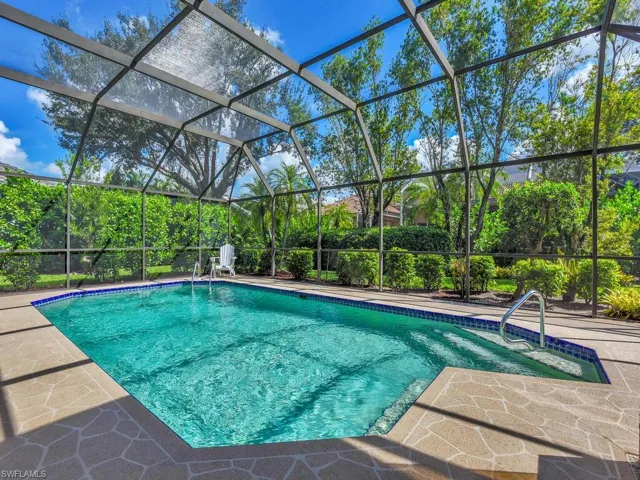 View of pool featuring glass enclosure and a patio