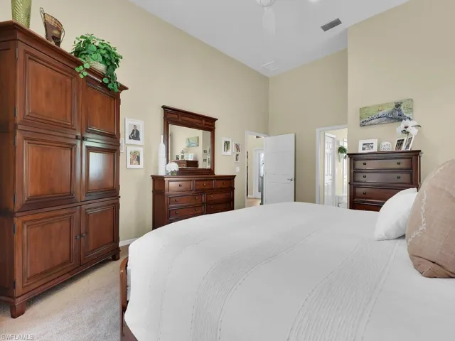 Carpeted bedroom featuring a towering ceiling, ceiling fan, and ensuite bathroom