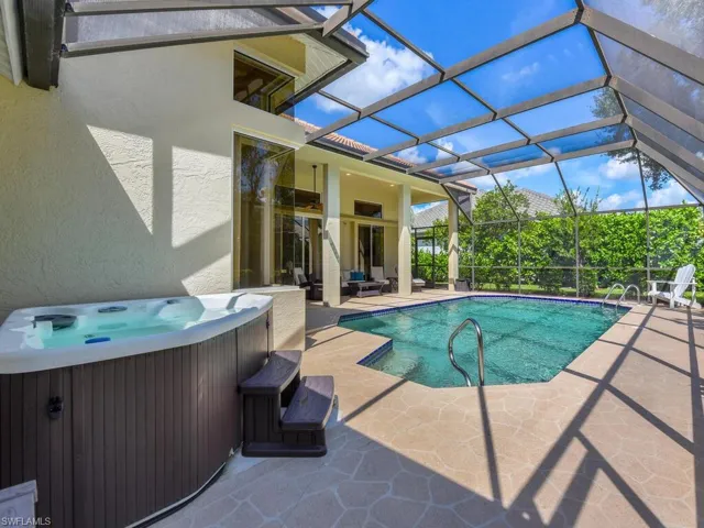 View of swimming pool with a lanai, a hot tub, a patio area, and central air condition unit