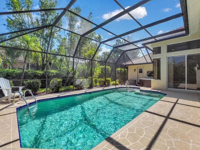 View of swimming pool featuring glass enclosure and a patio area
