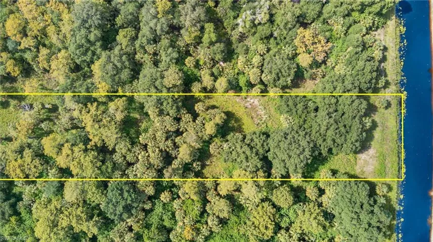 Aerial view of property and surrounding area featuring property boundaries highlighted and a large body of water
