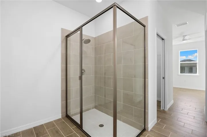 Full bath featuring a shower stall, wood tiled floors, and ceiling fan
