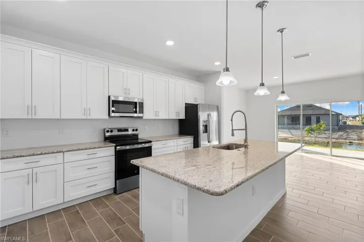 Kitchen featuring stainless steel appliances, white cabinetry, light stone counters, and wood tiled floors