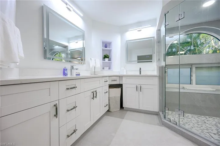 Bathroom with double vanity, a stall shower, and light tile patterned floors