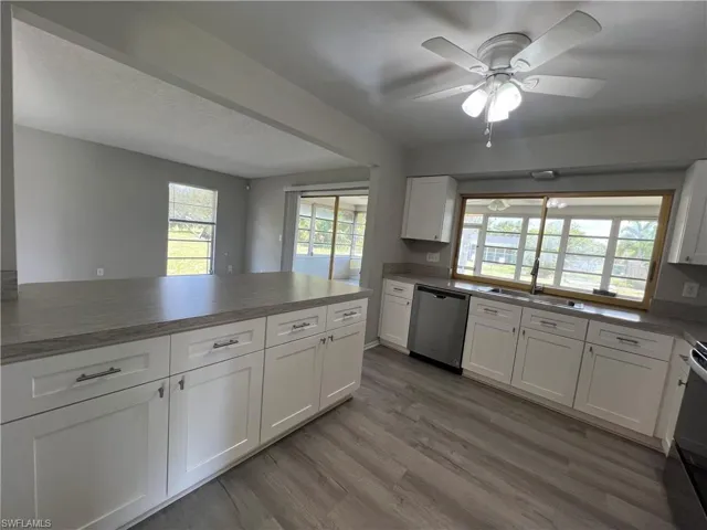 Kitchen featuring ceiling fan, stainless steel dishwasher, light wood-type flooring, sink, and white cabinets