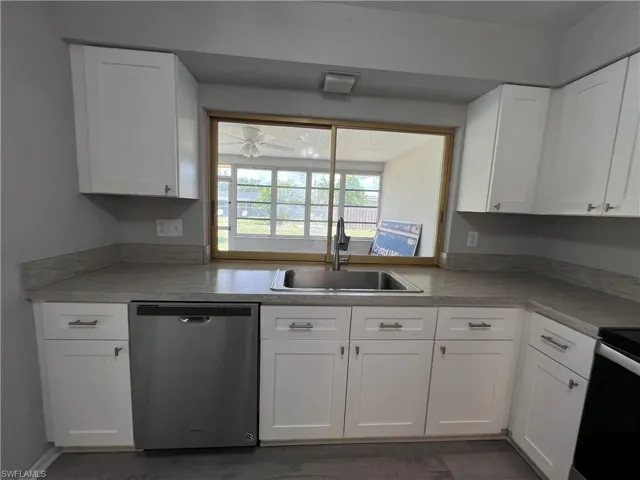 Kitchen with white cabinets, sink, and stainless steel dishwasher