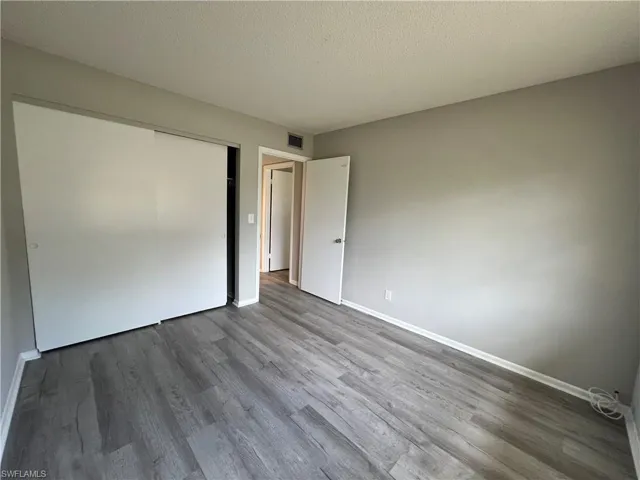 Unfurnished bedroom featuring hardwood / wood-style flooring, a closet, and a textured ceiling