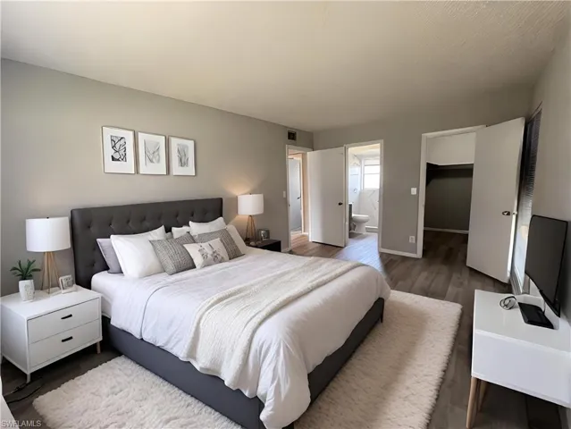 Bedroom with dark wood-type flooring, connected bathroom, a closet, and a spacious closet