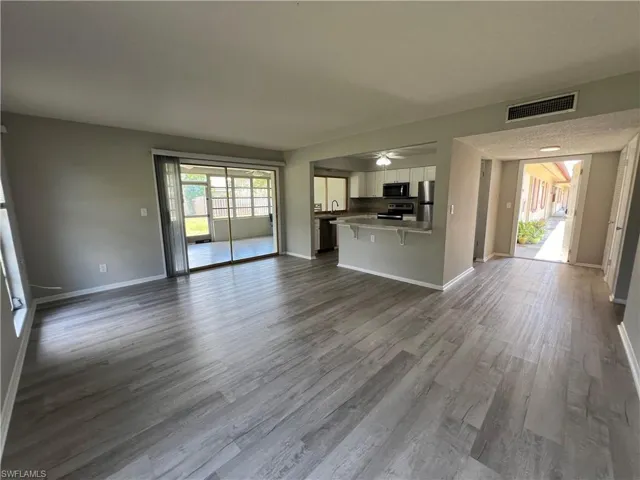 Unfurnished living room with ceiling fan, plenty of natural light, and hardwood / wood-style flooring