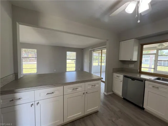 Kitchen with ceiling fan, stainless steel dishwasher, sink, hardwood / wood-style flooring, and white cabinetry