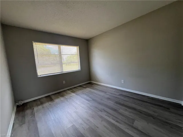 Unfurnished room featuring a textured ceiling and dark hardwood / wood-style floors