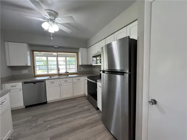 Kitchen featuring ceiling fan, stainless steel appliances, white cabinets, and wood-type flooring