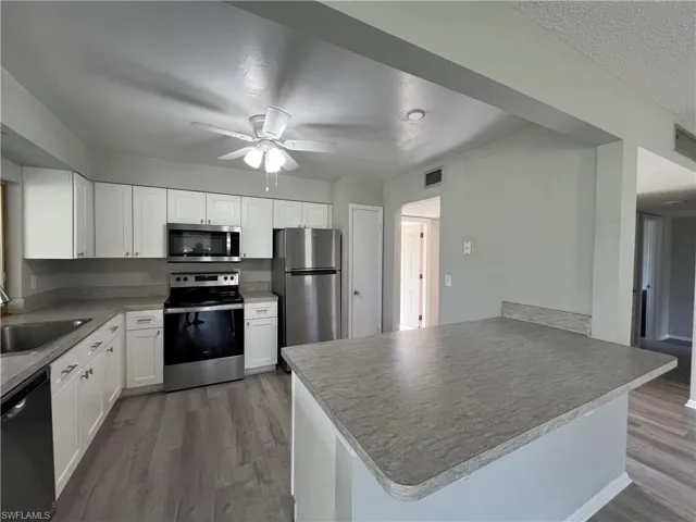 Kitchen with sink, white cabinets, hardwood / wood-style flooring, and stainless steel appliances