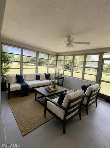 Enclosed sunroom featuring multiple large windows, a ceiling fan, and tile flooring