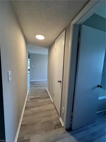 Corridor with a textured ceiling and wood-type flooring
