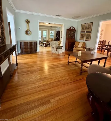Living area with crown molding and wood floors