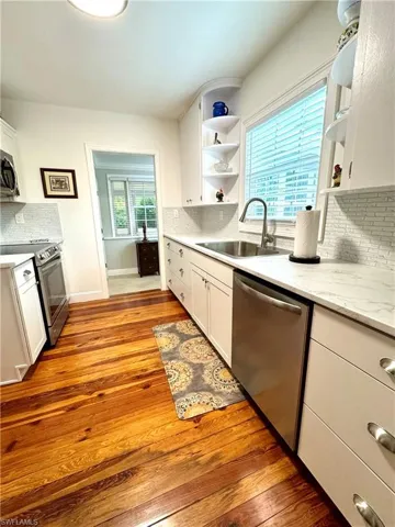 Kitchen with stainless steel appliances, open shelves, and decorative backsplash