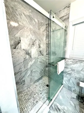 Bathroom featuring a marble-style finish shower