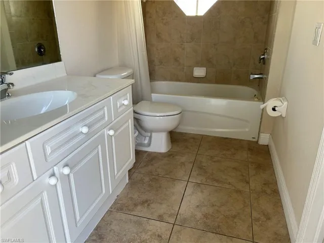 Bathroom featuring vanity, shower / bath combo with shower curtain, and light tile patterned floors