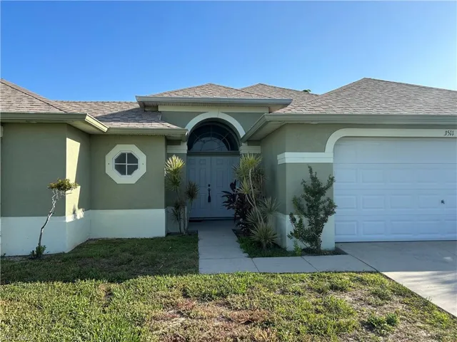 Property entrance with a garage, a lawn, stucco siding, driveway, and roof with shingles