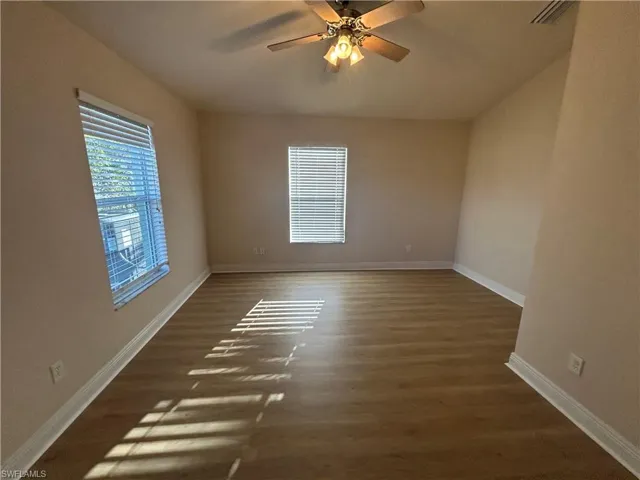 Unfurnished room featuring dark wood-style flooring and ceiling fan