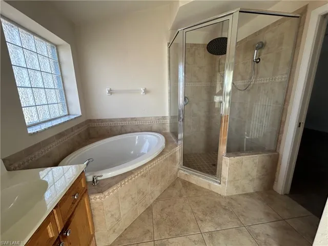 Full bathroom featuring a stall shower, a garden tub, vanity, and light tile patterned floors
